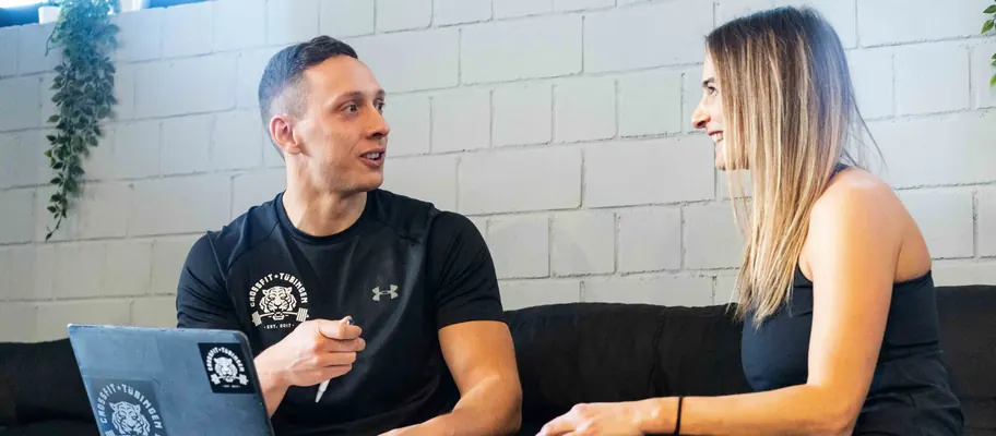 Coach bespricht mit einer Kundin auf dem Sofa ihren persönlichen Trainingsplan