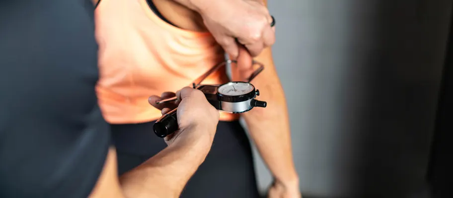 Coach misst mit einem Goniometer die Beweglichkeit am Arm einer Kundin